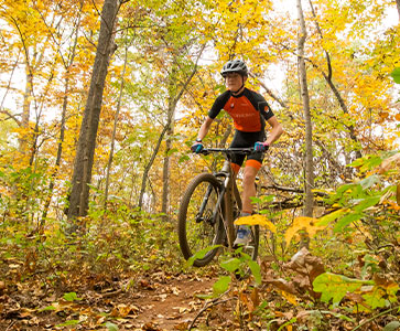 Student biking in the woods. Links to Gifts That Protect Your Assets